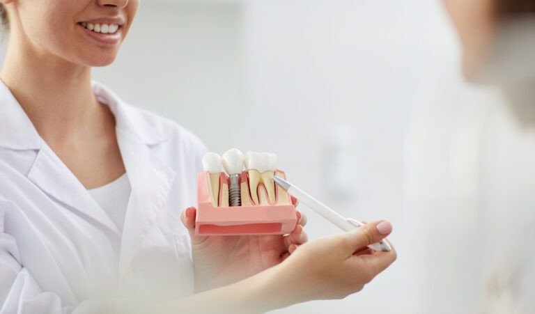 closeup,of,smiling,female,dentist,pointing,at,tooth,model,while